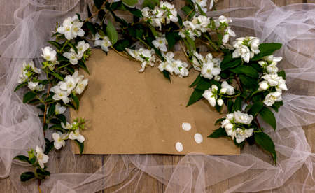 Kraft brown paper background place for text on a wooden background with a white grid and fresh white jasmine flowersの写真素材