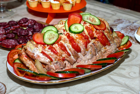 festive dish, baked stuffed meat with vegetables and cheese decorated with slices of tomatoes and...