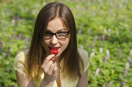 Portrait of beautiful girl with strawberry in spring forestの写真素材