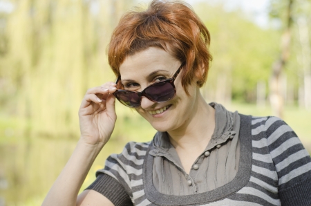 Portrait of beautiful smiling red hair girl with sun glassesの写真素材