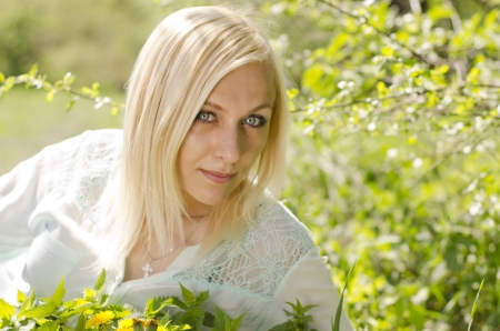 Portrait of beautiful blonde girl with  dandelion in parkの写真素材