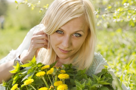 Portrait of beautiful blonde girl with  dandelion in parkの写真素材