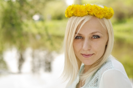 Portrait of beautiful blonde girl with wreath of dandelionの写真素材