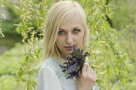 Portrait of beautiful blonde girl with lungwort flowers on willow tree backgroundの写真素材