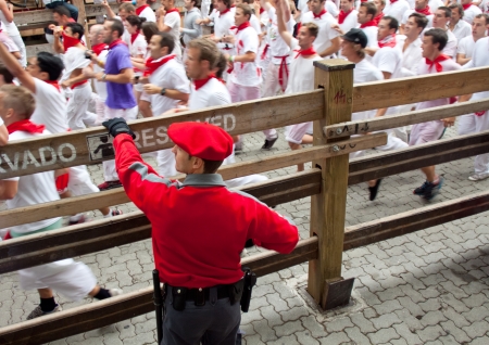 PAMPLONA, SPAIN -JULY 7: Police officer working at the festival of San Fermin. Street Estafeta. Pamplona, Navarra, Spain 7 July 2012 in Pamplona Spain.のeditorial素材