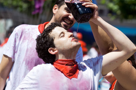 PAMPLONA, SPAIN - JULY 6: Man drinking red wine at opening of San Fermin festival. Plaza Consistorial in front of municipality. Pamplona, Navarra, Spain July 6, 2013のeditorial素材