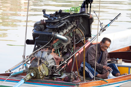 CRABI, THAILAND - JANUARY 28: Carrier tourists repairing motor on his boat taxi on beach Railay, Krabi, Thailand January 28, 2014. A common way of earning a living amongst local people in Thailandのeditorial素材