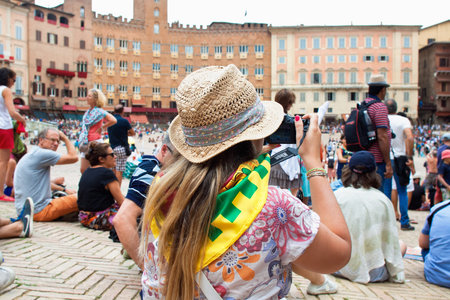 SIENA, ITALY - AUGUST 16: Spectators in anticipation of start of annual traditional Palio di Siena horse race in medieval square "Piazza del Campo" August 16, 2014 in Siena, Italyのeditorial素材
