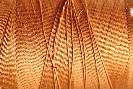 gold golden brown thread fabric wool yarn wrapped in a spool of threads and textiles great for a backgroundの写真素材
