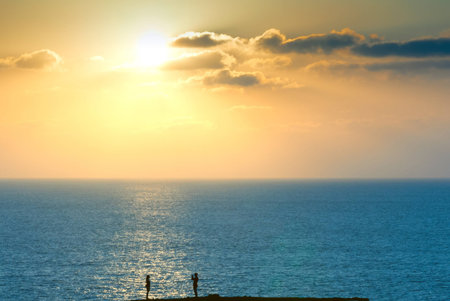 A guy takes a photo of his girlfriend under the sunset light