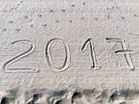A shot of the year 2017 /numbers) engraved in the sand of a beach