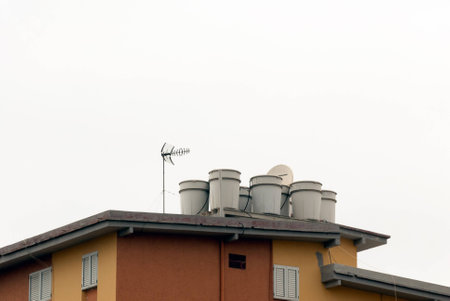 A shot of a group of water drums in a roof beside TV antennasの写真素材