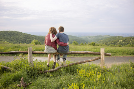 Rear view couple hugging landscape mountains.の写真素材