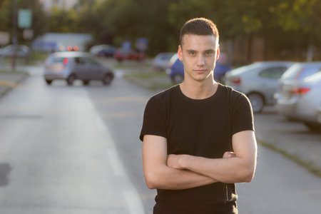 Young man in 20s serious expression, arms crossed. Background out of focus.の写真素材