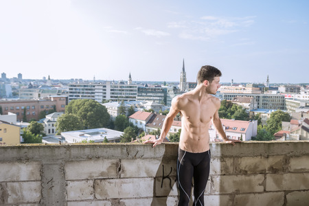 fitness man fit model leaning on wall city shirtlessの写真素材
