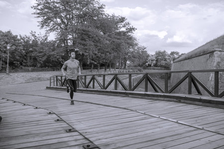 young man running jogging  outdoors nature bridge