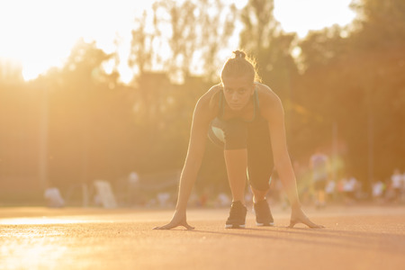 teenage girl start sprint position runner athlete sunny lens flare yellowの写真素材
