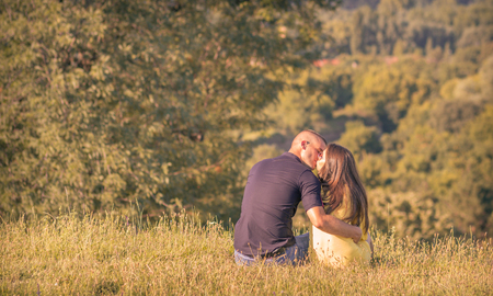 kissing young couple back rear view outdoors sunny forest mountainの写真素材
