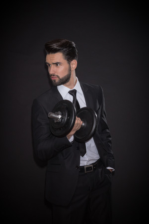 one young handsome man fitness dumbbell exercise, black background, elegant suit tie shirt pants jacketの写真素材