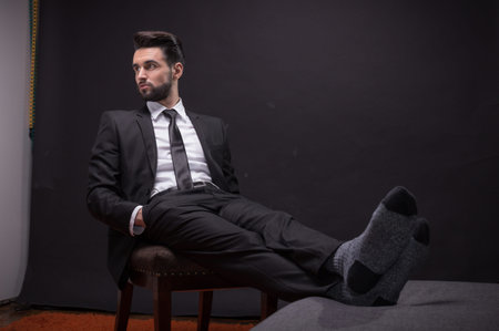 one young adult man handsome sitting chair relaxing socks suit elegant shirt tie pants