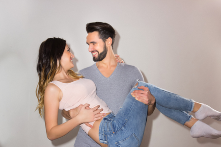 two people, candid portrait couple man holding woman arms happy smiling, casual clothes, white backgroundの写真素材