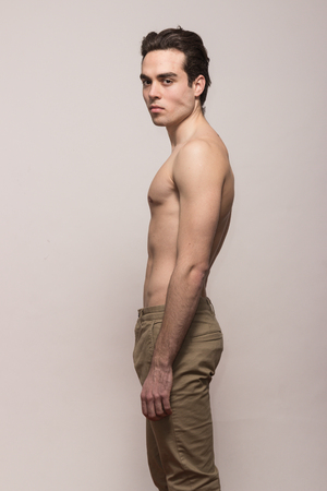 one young adult man model shirtless body posing pants, white backgroundの写真素材