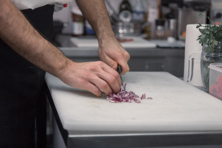 young adult man, chef cutting board, onions professional commercial kitchenの写真素材