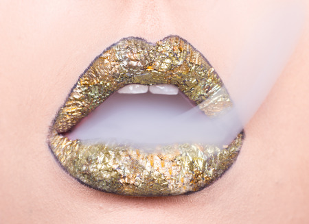 golden lips, open mouth, woman closeup, smokeの写真素材