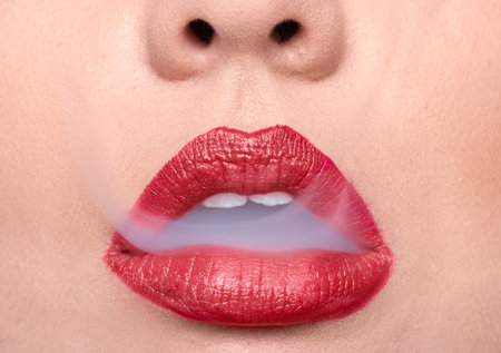 woman skin lips, red lipstick, smoke coming out of mouth, unrecognizable personの写真素材