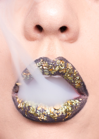 black lipstick, open mouth closeup, woman skin lips golden, smokeの写真素材