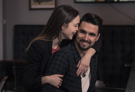young woman hugging man, looking at camera smiling, dark pubの写真素材