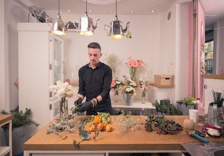 one young adult man, florist, arranging flowers, flower shop indoorsの写真素材
