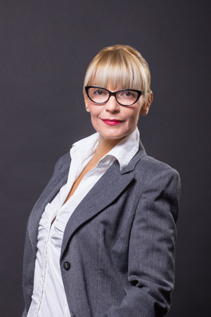 mature woman 40s cheerful eyeglasses studio black background white shirt gray coatの写真素材