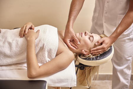 man physiotherapist hands, massage woman face head.の写真素材