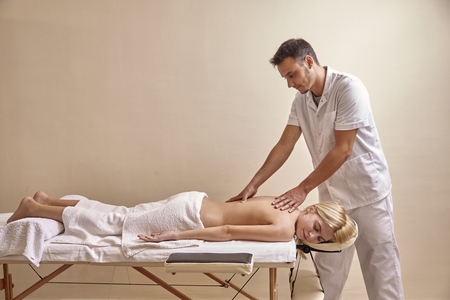 physiotherapist massage, woman back. full lenght shot, indoors. wall, copy space.の写真素材