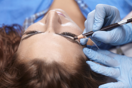 microblading, woman drawing with pencil eyebrow shape, close upの写真素材