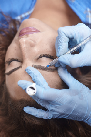microblading close-up, hands adding pigment to eyebrows.の写真素材