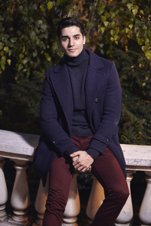 one handsome young man, 20-29 years old, posing, autumn clothes, looking to camera, sitting on street marble fence. night time, dark.の写真素材