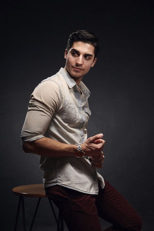 one young handsome man, handsome model, 20-29 years old, posing in studio, photo shoot. black background. casual clothes. wearing jeans shirt.の写真素材