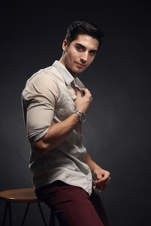 one young handsome man, handsome model, 20-29 years old, posing in studio, photo shoot. black background. casual clothes. wearing jeans shirt.の写真素材