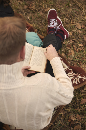 one young man, hipster reading book, in rural area, sitting in mountain field outdoors. elevated view, view from above.の写真素材