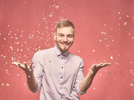 one young man, 20-29 years old, candid smiling happy, throwing confetti flying in air. real person, not model. pink background, studio shot, photo shoot.の写真素材