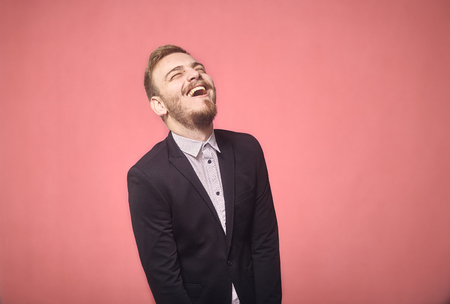 one young man, 20-29 years old, candid laughter, laughing. pink background, studio shot, photo shoot.の写真素材