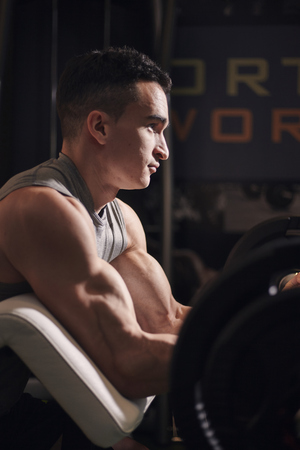 one young man, side view of him exercising in gym, muscular bicep and arm muscles. close-up shot, abstract.の写真素材