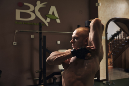 one man bodybuilder, upper body, exercise: "Seated Single Arm Overhead Dumbbell Tricep Extensions".の写真素材