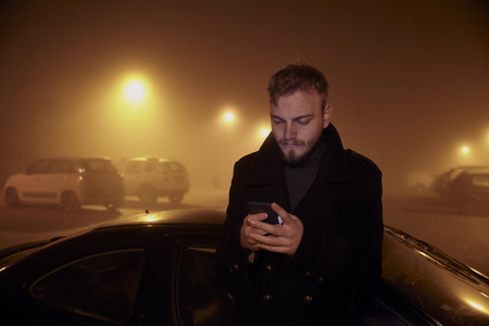 one young man, using smart-phone in dark night mist.の写真素材