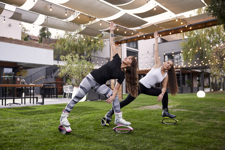 two young ladies, 20-29 years old, doing some kind of exercise in jump boots,in a backyard of a fancy house.の写真素材