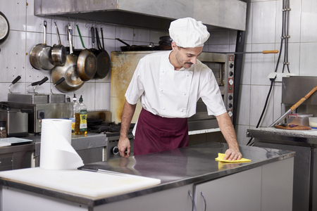 young chef in kitchen cleaning working table, after closing restaurant.の写真素材