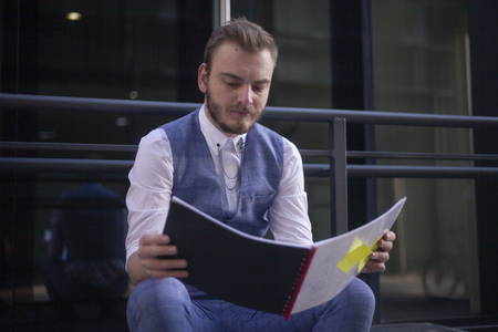 one young man, 20-29 years old sitting and reading from his notebook.front view.の写真素材