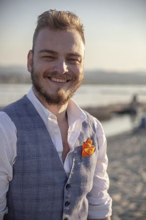 one young man, upper body portrait, generously smiling, on a beach. Sunny day outdoors.の写真素材